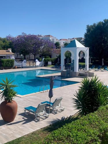 a swimming pool with two chairs and a gazebo at Villa c/ piscina próxima da praia in Cabanas de Tavira
