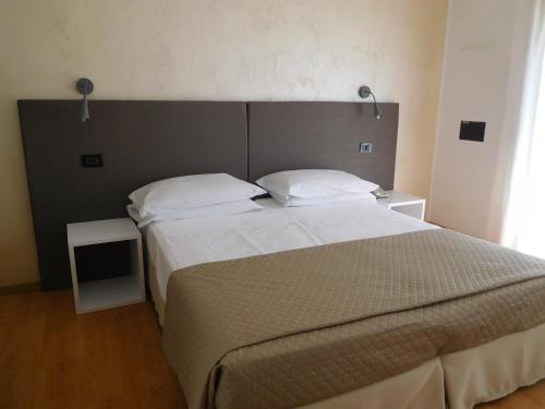 a bedroom with a large bed with white sheets and pillows at Hotel Emperador in Lido di Jesolo