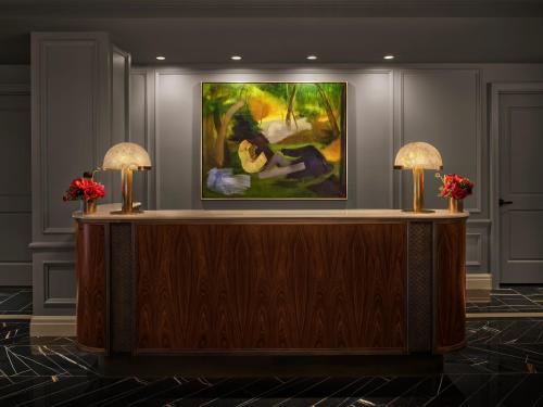 a reception desk in a lobby with a painting on the wall at The Newbury Boston in Boston