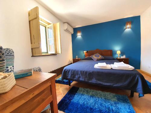 a bedroom with blue walls and a bed with two rugs at Comporta Family House in Comporta