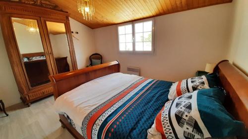 - une chambre avec un lit doté d'une tête de lit en bois et d'un miroir dans l'établissement Charmante maison de ville avec jardin - 2 chambres - 5 pers, à Saint-Jean-de-Monts