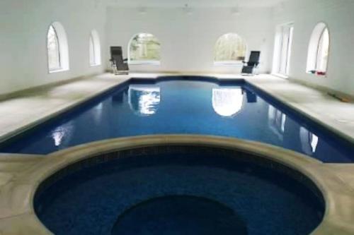 a large swimming pool with blue water in a building at Historic Manor House - Sleeps 16 - Pool & Hot Tub in Rochester