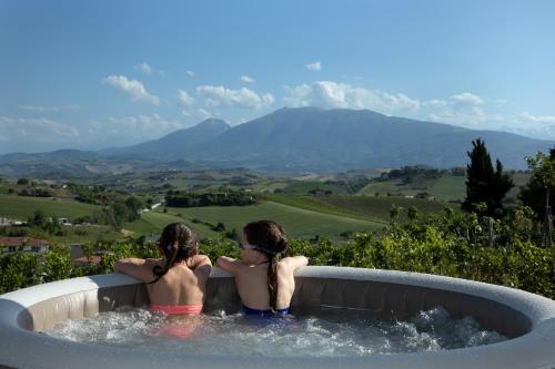 two girls sitting in a hot tub with a view at Residence Borgo Offida in Offida
