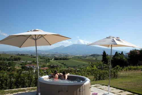 two people sitting in a hot tub under two umbrellas at Residence Borgo Offida in Offida