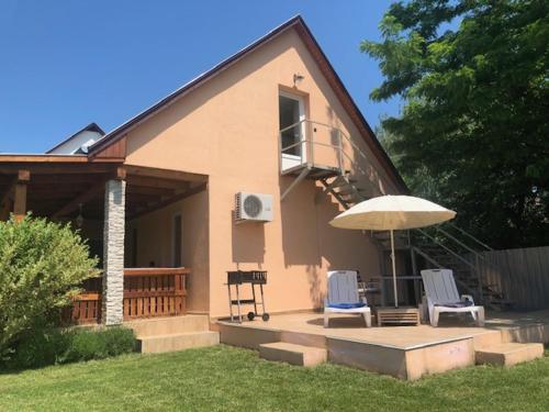 a house with a patio with two chairs and an umbrella at Gere House in Siófok