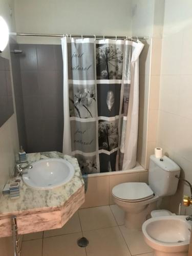 a bathroom with a sink and a toilet and a shower curtain at Magnólia Mar 302 in Lagos