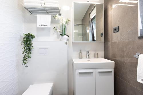 a white bathroom with a sink and a mirror at Villa Supernus II in Baška