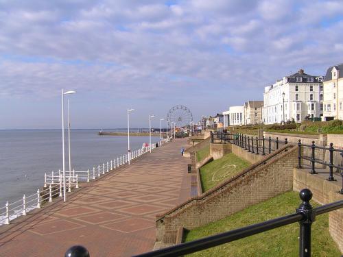 a boardwalk next to the ocean with a roller coaster at 2 Beach House in Bridlington