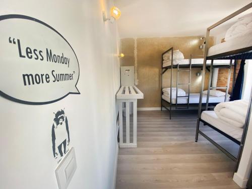 a room with bunk beds with a sign that says less money more summer at ECO Hostel in Granada