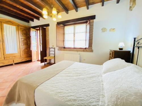 um quarto com uma grande cama branca num quarto em La Helguera Vivienda Vacacional em Villanueva