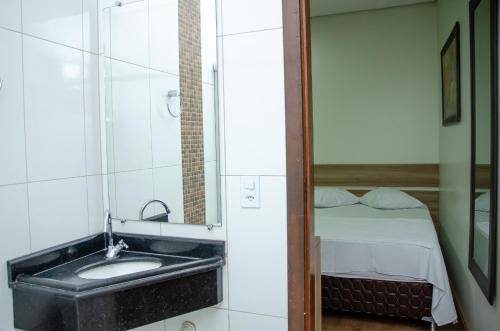 un bagno con un lavandino e un letto di Hotel Della Vita a Glória de Dourados