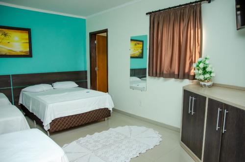 una camera da letto con due letti e uno specchio di Hotel Della Vita a Glória de Dourados