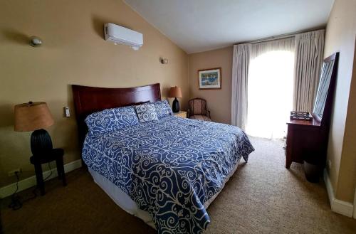 a bedroom with a bed with a blue comforter and a window at La Casa Rosa in Ensenada