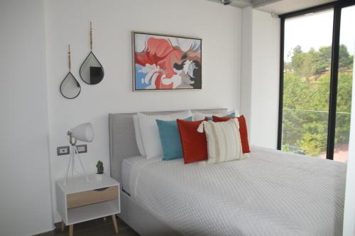 a white bedroom with a bed and a window at Cozy Stays Cayala Apartments 5 in Guatemala