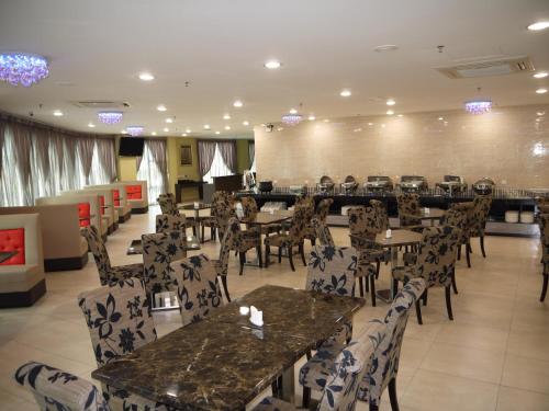 ein Restaurant mit Tischen und Stühlen in einem Zimmer in der Unterkunft MidCity Hotel Melaka in Malakka