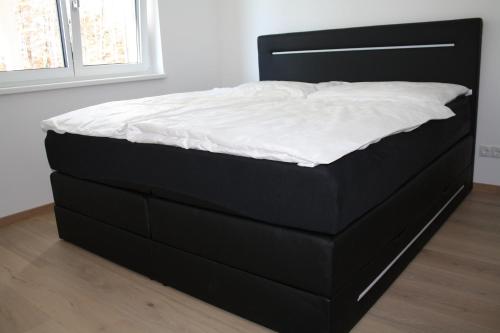 a black bed with white sheets on it in a room at Moderne Gartenwohnung nähe LKH Univ Klinikum Graz in Graz