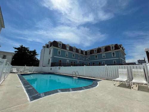 a building with a swimming pool in front of a fence at Wildwood Inn, a Travelodge by Wyndham in Wildwood