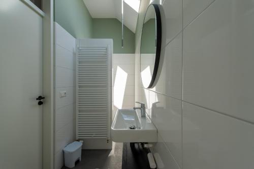 a white bathroom with a sink and a mirror at Huize Kreek en Zee in Westkapelle