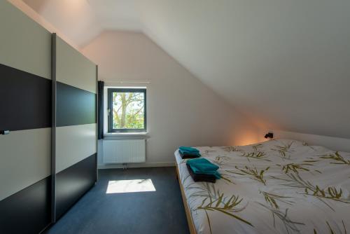 a bedroom with a bed and a window at Huize Kreek en Zee in Westkapelle