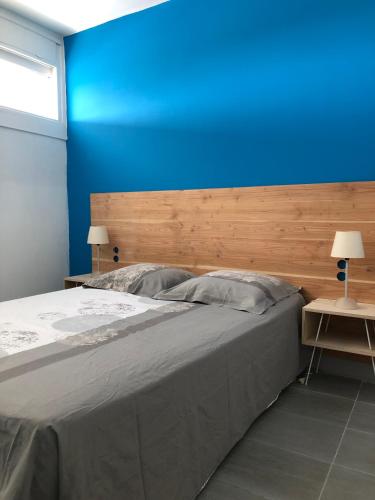 une chambre avec un grand lit avec un mur bleu dans l'établissement Appartement naturiste PaulAna Port Ambonne 314, au Cap d'Agde