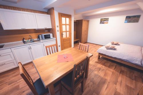a kitchen and dining room with a table and a bed at Penzion Horský statek in Šumavské Hoštice