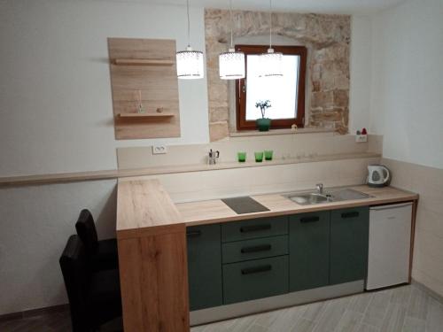 a kitchen with green cabinets and a sink and a window at Studio apartment Iva in Bale