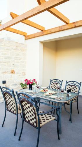 a table with four chairs and a table with flowers on it at Kastro Apartments in Panormos Rethymno