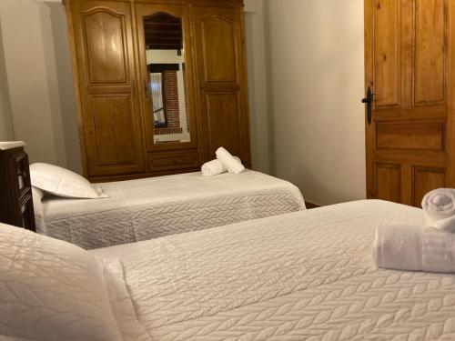 a bedroom with two beds and a wooden cabinet at La Helguera Vivienda Vacacional in Villanueva