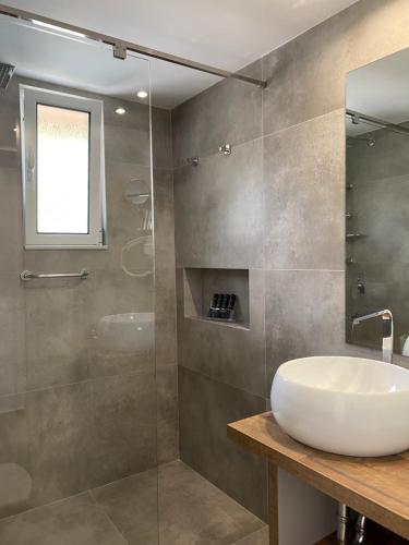 a bathroom with a sink and a glass shower at Golden View Residence in Dhërmi
