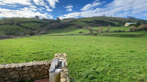a stone wall in a field with green hills at La Helguera Vivienda Vacacional in Villanueva