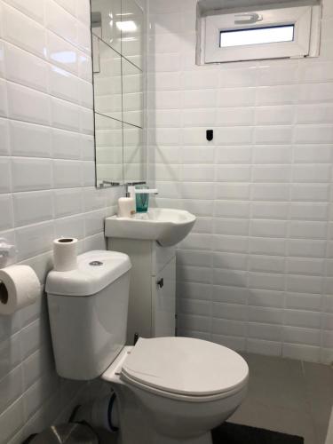 a white bathroom with a toilet and a sink at Robert Local Social Restaurant & Accomodation in Hîrşova