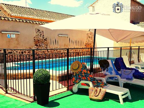 a patio with chairs and an umbrella next to a pool at Casa Rural Hidalgo in Ciudad Real