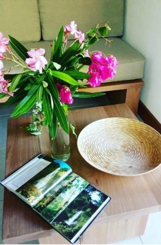 a table with a vase of pink flowers and a plate at Un cosy sous le vent in Gourbeyre