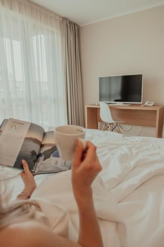 a woman laying on a bed reading a book at St. Panteleimon Beach Hotel in Nesebar