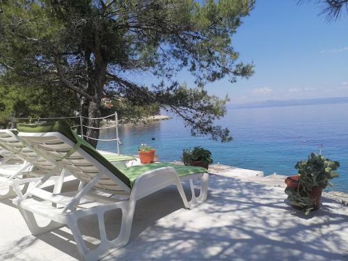 a pair of lawn chairs sitting on a patio near the water at Apartment D&D in Prigradica