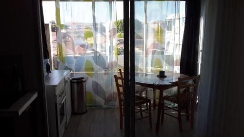 une table et des chaises dans une cuisine avec une fenêtre dans l'établissement 2 pièces - Cabine et terrasse Véranda - GRAU DU ROI -, au Grau-du-Roi