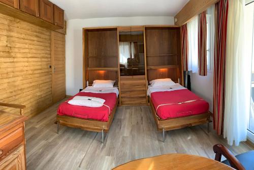 two beds in a room with wooden walls and wood floors at ANTONIA2 in Brides-les-Bains
