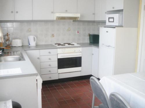 kuchnia z białymi szafkami, kuchenką i lodówką w obiekcie Redwood Apartment w Killarney