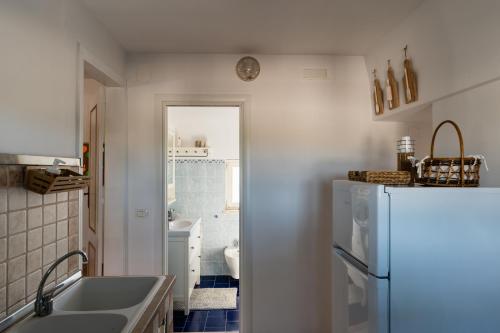 La cuisine est équipée d'un réfrigérateur blanc et d'un évier. dans l'établissement Il pergolato sul mare, à Monopoli