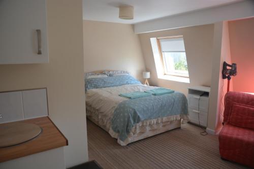 a bedroom with a bed and a window and a red chair at The Garrett in Melcombe Regis