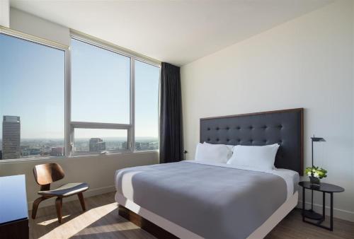 a hotel room with a bed and two windows at Luxury Highrise Living Downtown LA in Los Angeles