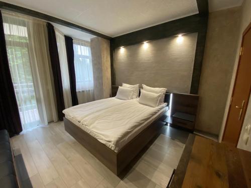 um quarto com uma cama grande com lençóis brancos e almofadas em Deluxe 217 em Borovets