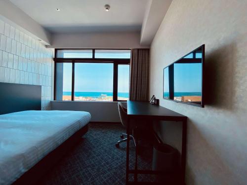 那覇市にあるHotel Cocktail Stay Nahaのベッド、デスク、窓が備わるホテルルームです。