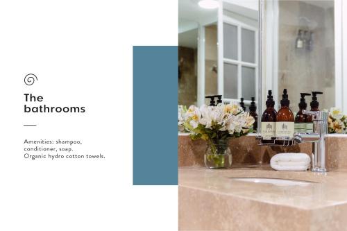 a bathroom sink with bottles of alcohol and flowers at Jardín Roma By The Local Way in Mexico City