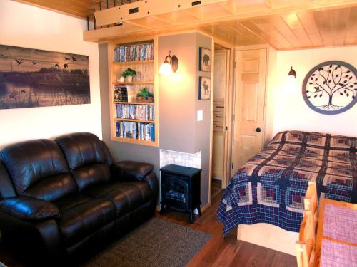 a bedroom with a bed and a leather couch at Prairie Rose Cottage in Fort Macleod