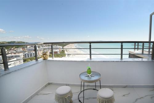 a balcony with a table and stools on a building at Beachfront Marilyn in Durrës