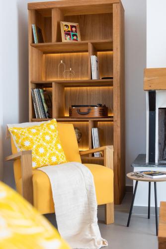 a yellow chair in front of a book shelf at The Be House in Sifnos