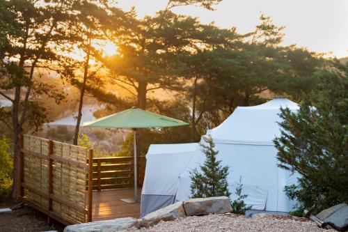 a wooden deck with an umbrella and two tents at Salema Eco Camp - Sustainable Camping & Glamping in Salema