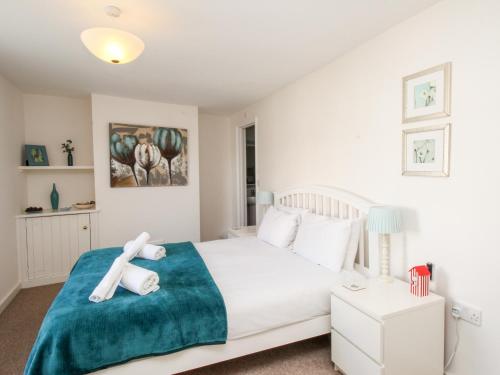 a bedroom with a white bed with a blue blanket at Firkin Cottage in Weymouth