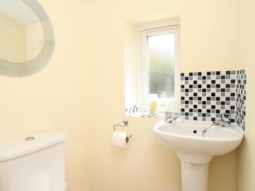 a bathroom with a sink and a toilet and a window at Firkin Cottage in Weymouth